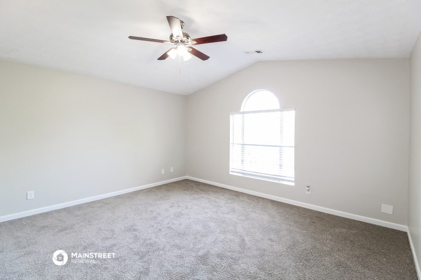 an empty living room with a ceiling fan and a window