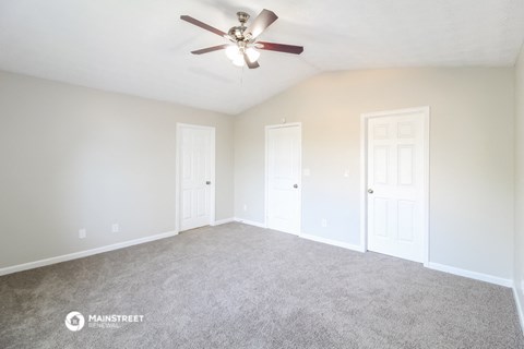 the spacious living room with carpet and ceiling fan