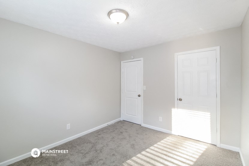 a bedroom with a white door and a carpeted floor