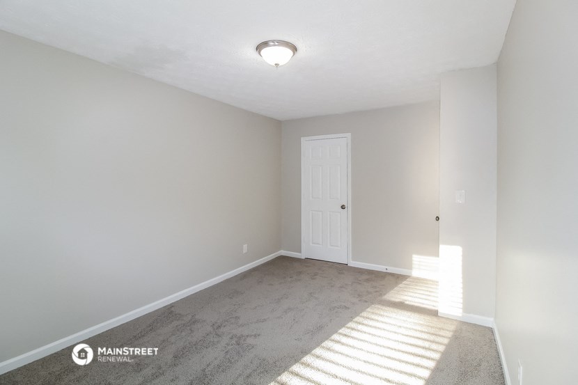 the spacious living room with carpet and a white door