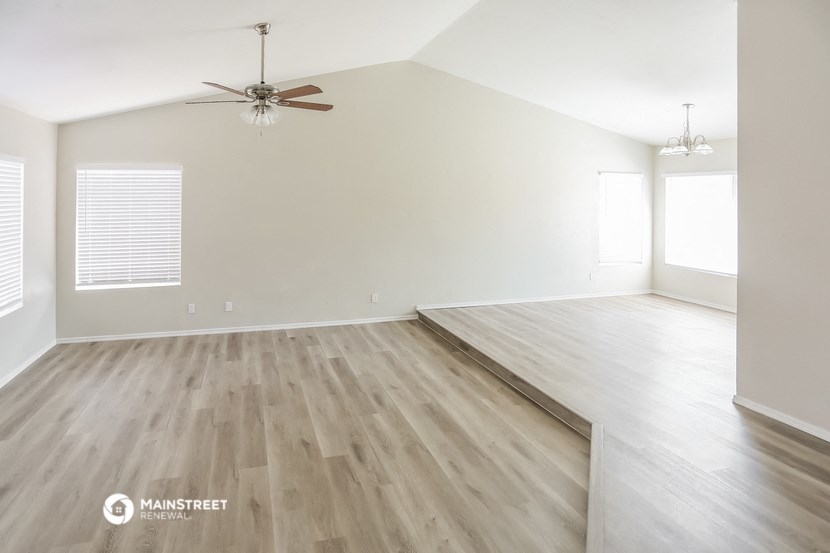 an empty living room with wood floors and a ceiling fan