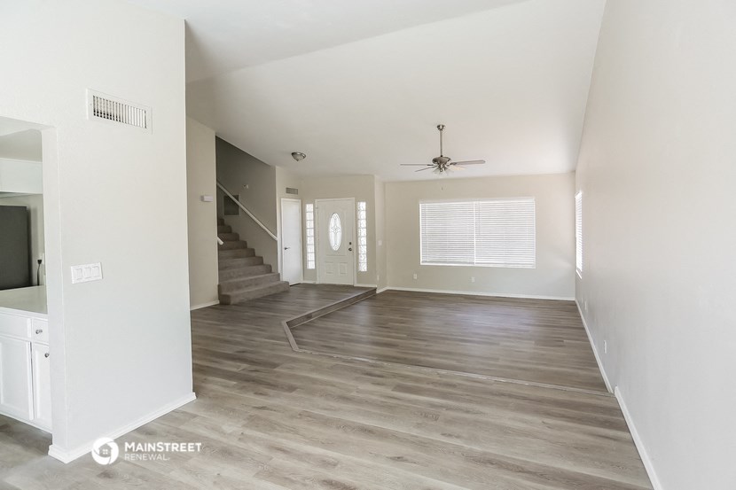 an empty living room with white walls and a ceiling fan