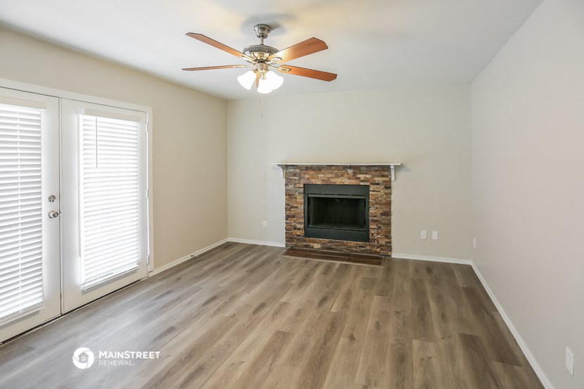 an empty living room with a fireplace and a ceiling fan