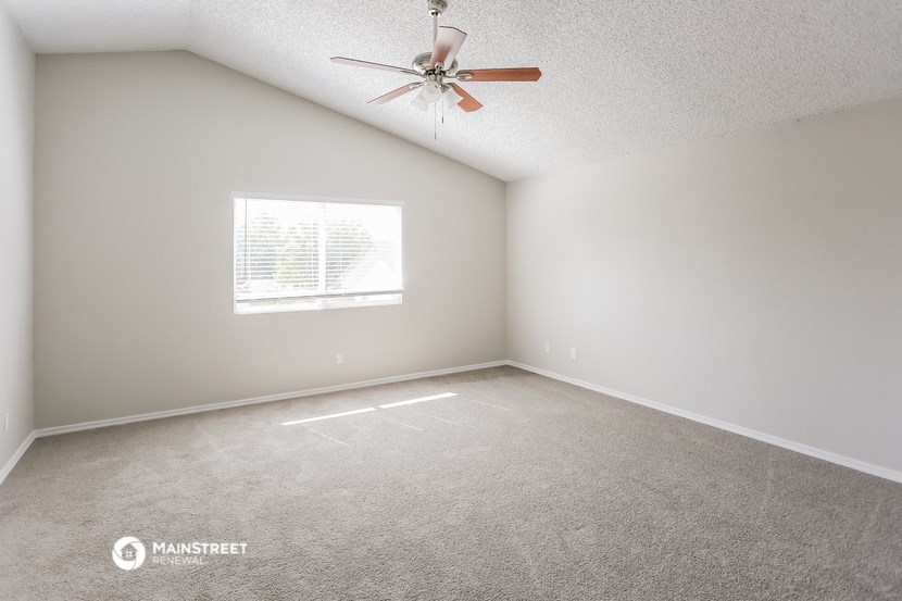 an empty room with a ceiling fan and a window