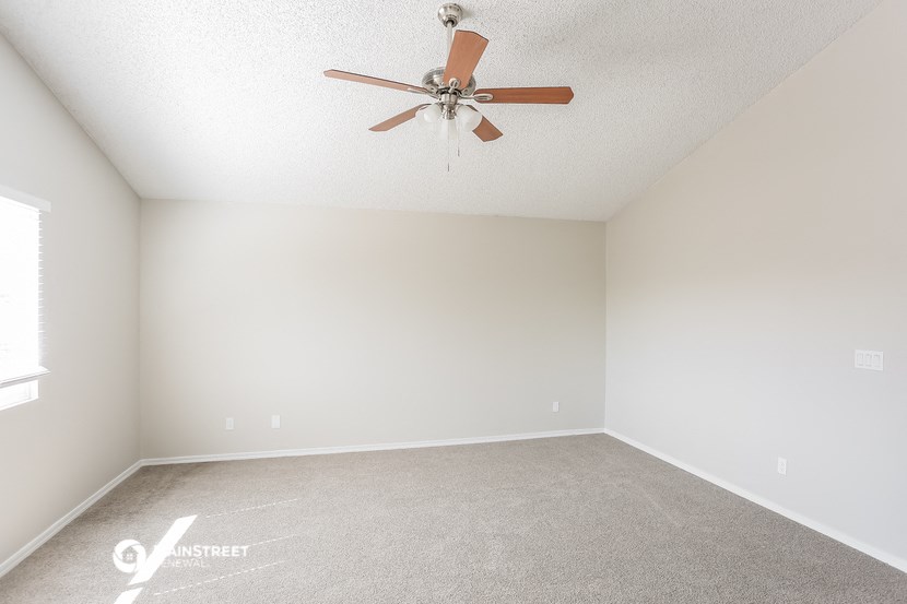 an empty living room with a ceiling fan