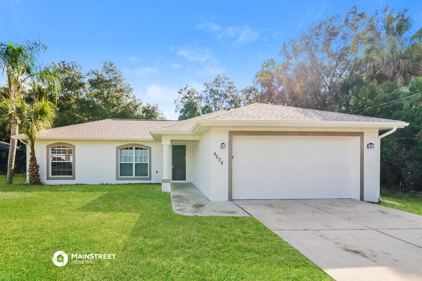 a white house with a driveway and a palm tree