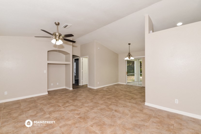the spacious living room with ceiling fan and tile flooring