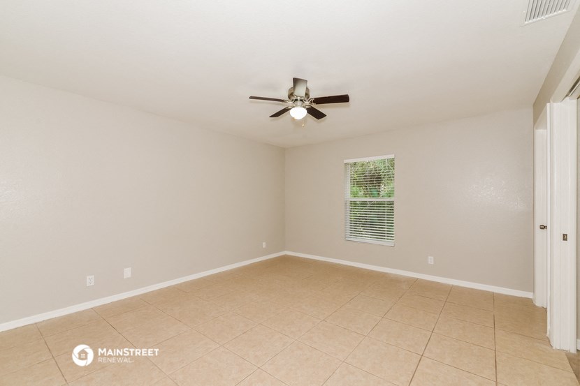 the spacious living room with ceiling fan and tiled floor
