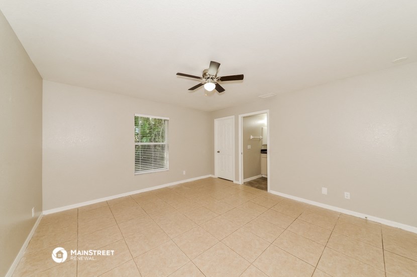 a spacious living room with tile flooring and a ceiling fan
