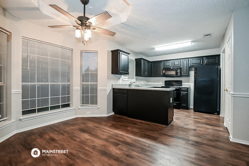 an empty kitchen with a large window and a ceiling fan
