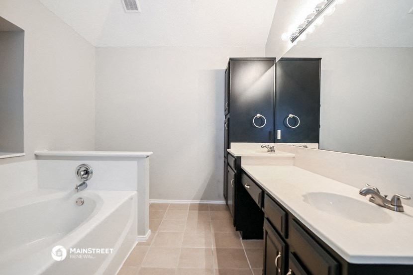 a bathroom with a tub and a sink and a mirror