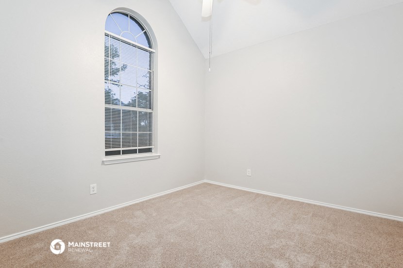 a bedroom with a large window and carpeting