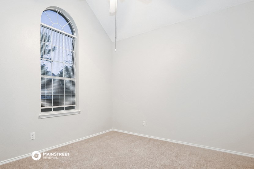 a bedroom with a large window and white walls