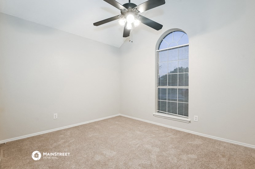 an empty room with a ceiling fan and a window