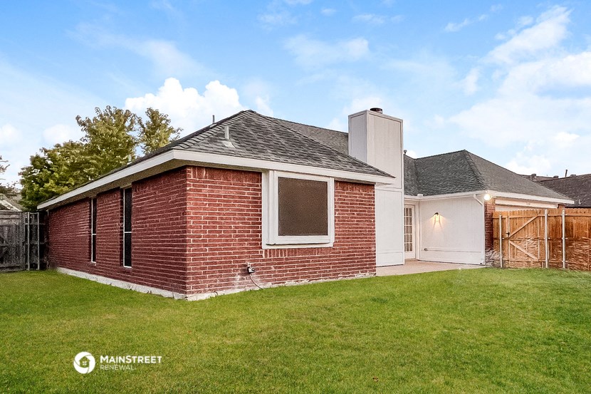 a small brick house with a yard and a fence
