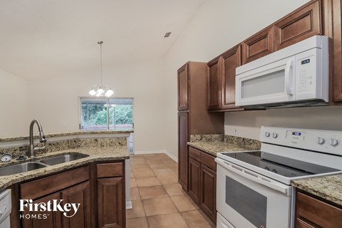 A kitchen with brown cabinets and a white microwave above the stove.