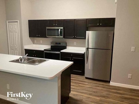 A kitchen with a white counter top and a stainless steel refrigerator.