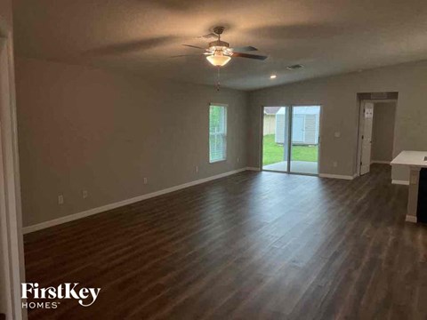 A spacious room with wooden floors and a ceiling fan.
