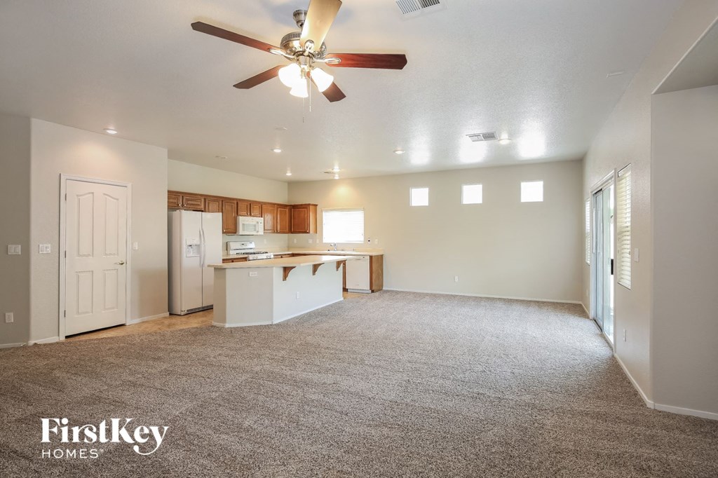 A spacious living room with a carpeted floor and a ceiling fan.
