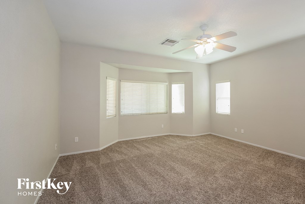 A spacious room with a carpeted floor and a ceiling fan.