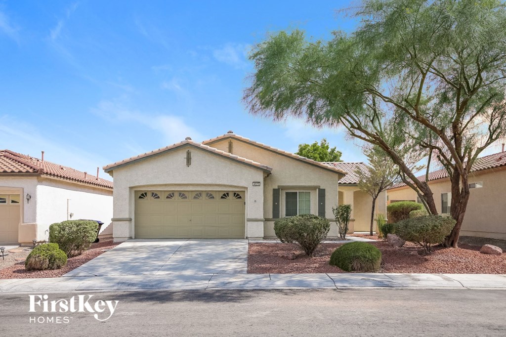 A house with a garage and a tree in front of it.