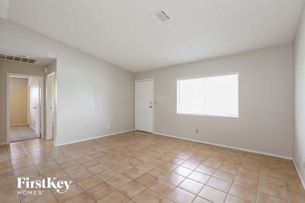 a spacious living room with tile flooring and white walls