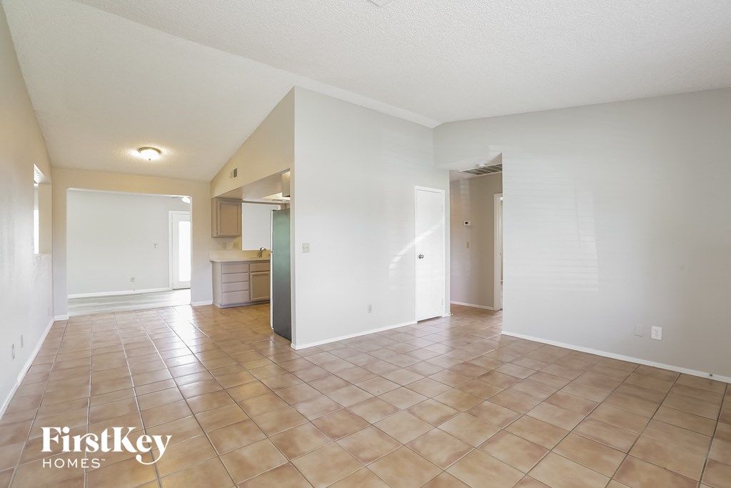 the living room and kitchen are spacious with tile flooring and white walls