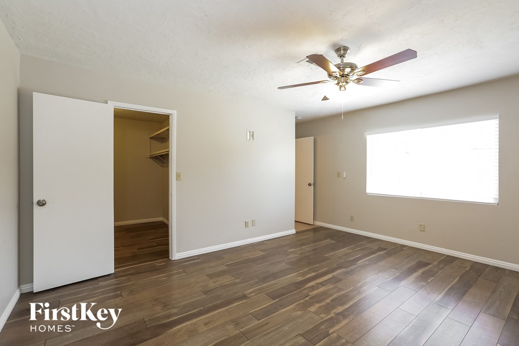the spacious living room with hardwood flooring and a ceiling fan