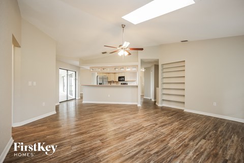 an empty living room with wood flooring and a ceiling fan
