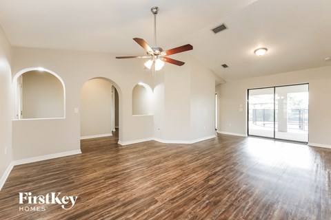 an empty living room with hardwood floors and a ceiling fan