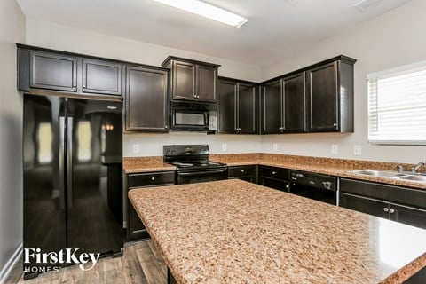 a kitchen with black cabinets and granite counter tops and black appliances