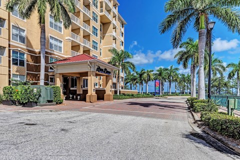 A building with a red roof and palm trees in front.