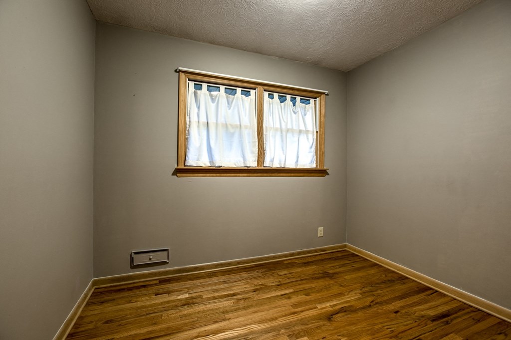 an empty room with wooden floors and a window