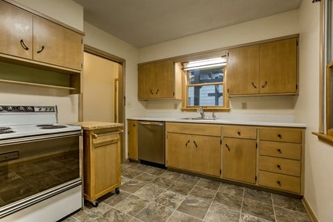 a kitchen with a stove and sink and wooden cabinets