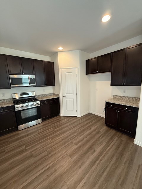 A kitchen with dark brown cabinets and a white door.