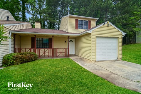A yellow house with a garage door and a brown fence.