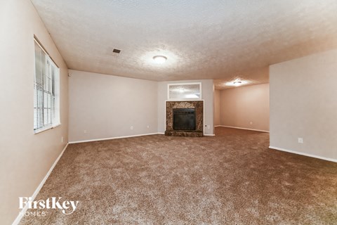 A spacious living room with a fireplace and carpeted floor.