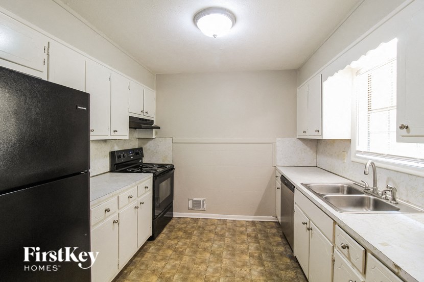 a kitchen with white cabinets and black appliances