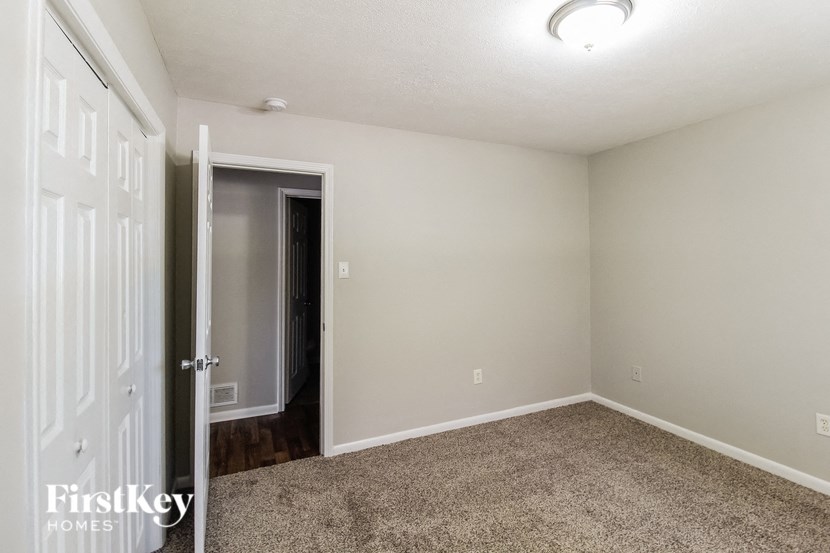 a bedroom with a carpeted floor and a door to a closet