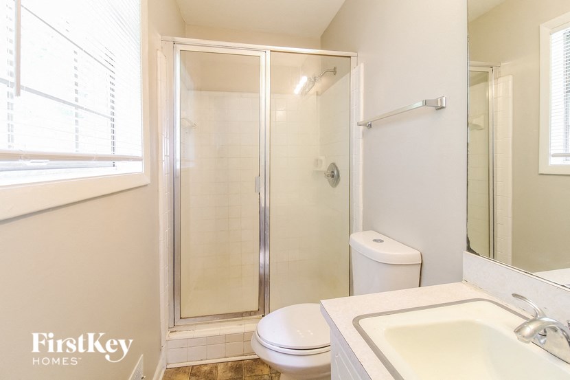 a bathroom with a shower toilet and sink and a window