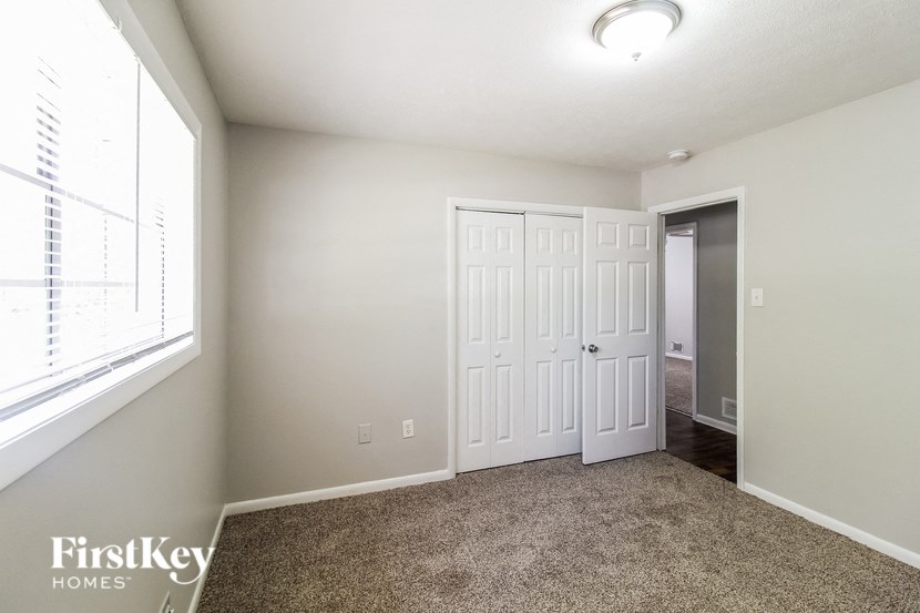a bedroom with two closets and a window and a carpeted floor
