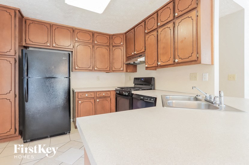 A kitchen with brown cabinets and a black fridge.