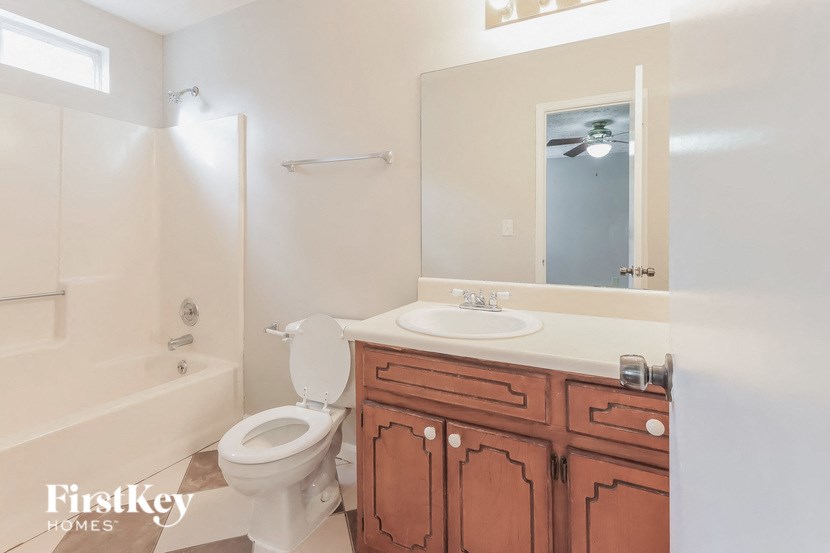 A bathroom with a toilet, sink, and mirror.