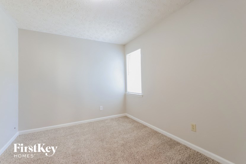 A room with a carpeted floor and a window letting in light.