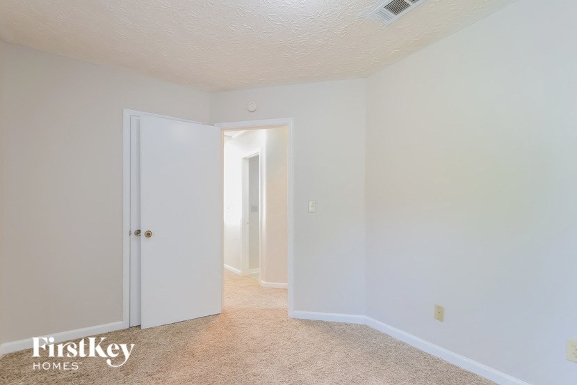 A carpeted hallway with a door on the left and a window on the right.