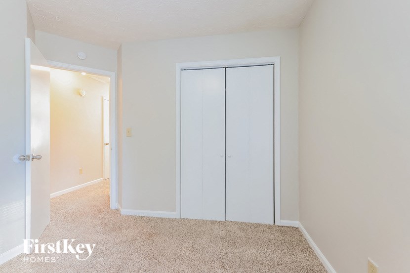 A bedroom with a carpeted floor and a white closet.