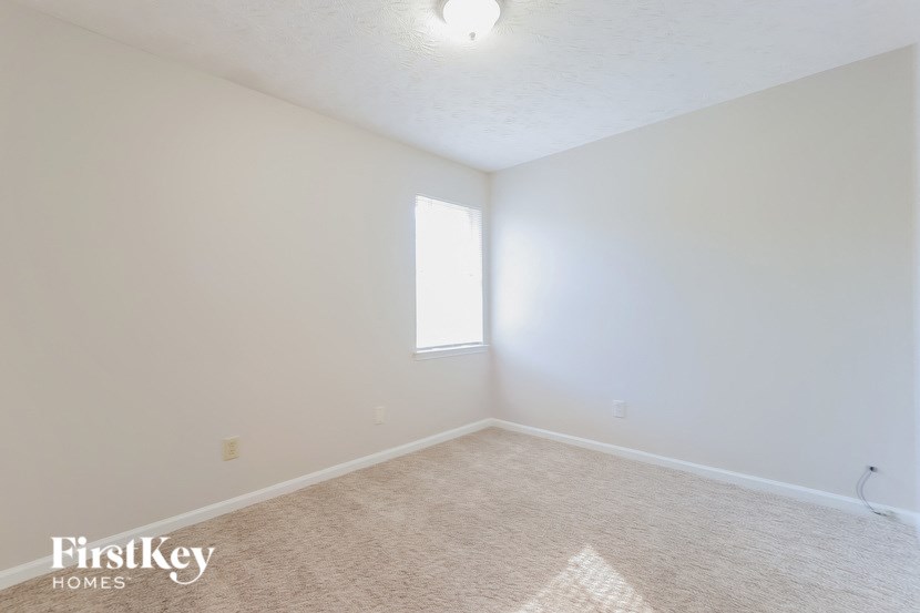A white room with a window and a carpet on the floor.