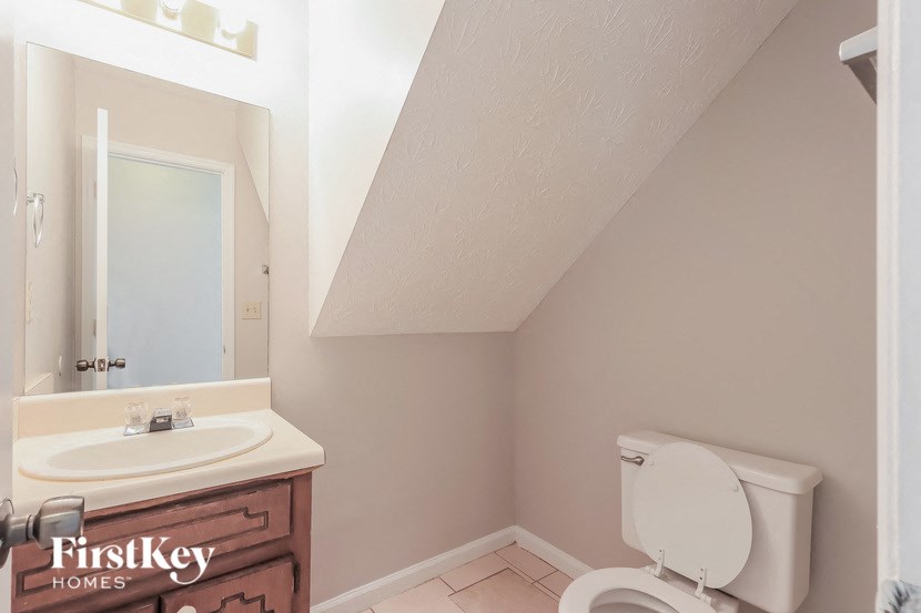 A white toilet in a small bathroom with a sink and mirror.