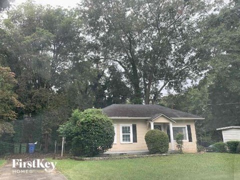 a small white house with a yard and trees