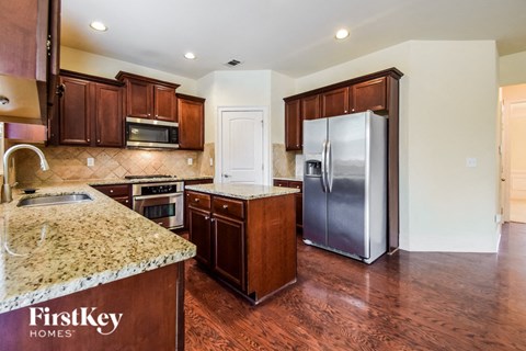 a kitchen with wooden cabinets and granite counter tops and a stainless steel refrigerator